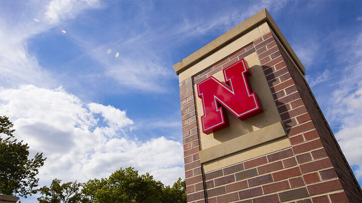 Nebraska N logo on pillar with sunny sky behind in the background