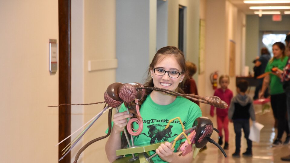 student with larger than life sized model of a mosquito